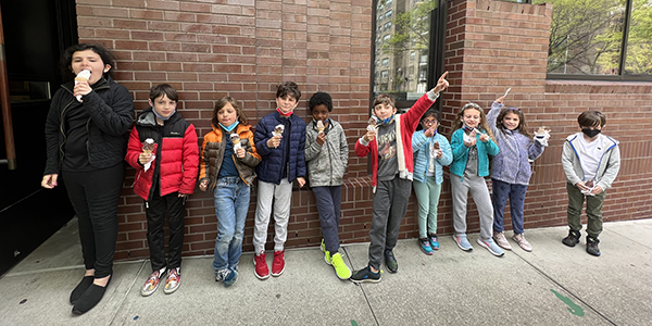 Students lined up against the outside of the North building, eating ice cream.