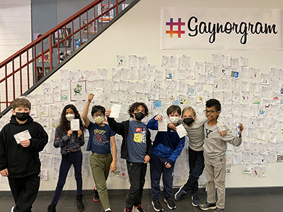 A group of students posing in front of the #Gaynorgram wall.