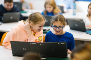 Two students huddle over their chromebooks.